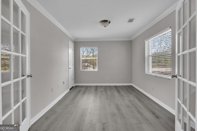 spare room with crown molding, visible vents, wood finished floors, french doors, and baseboards