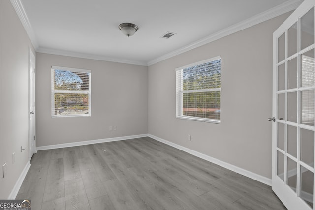 empty room with visible vents, baseboards, crown molding, and wood finished floors