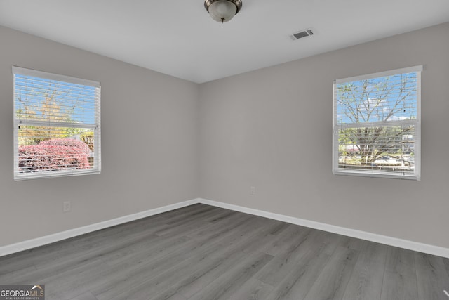 empty room featuring visible vents, baseboards, and wood finished floors