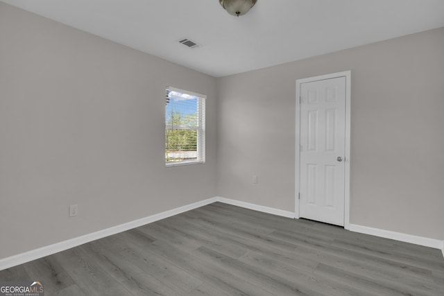 spare room featuring visible vents, baseboards, and wood finished floors