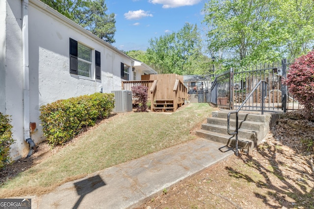 view of yard featuring a wooden deck, fence, and central AC