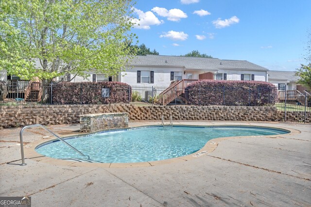 pool with fence, a patio, and stairs