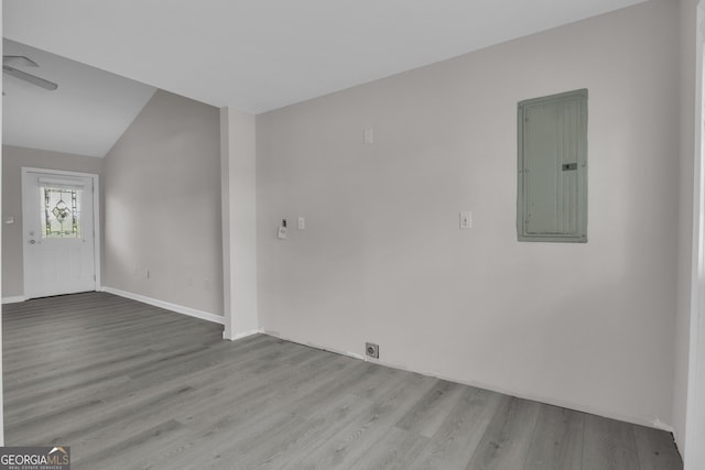 empty room with wood finished floors, baseboards, and electric panel