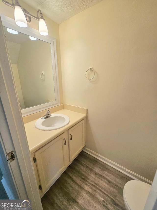 1557 Springleaf Ct SE, Smyrna, GA 30080 - bathroom with vanity, toilet, baseboards, a textured ceiling, and wood finished floors
