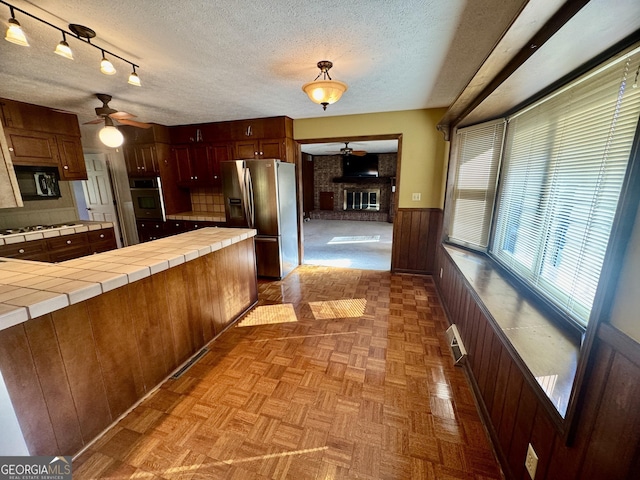 839 Golf Dr, Swainsboro, GA 30401 - kitchen featuring wooden walls, a textured ceiling, stainless steel appliances, a ceiling fan, and tile countertops