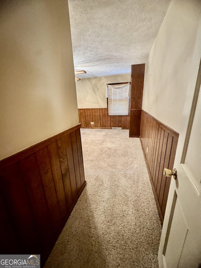 839 Golf Dr, Swainsboro, GA 30401 - hallway with wooden walls, a wainscoted wall, carpet flooring, and a textured ceiling