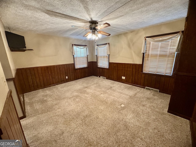 839 Golf Dr, Swainsboro, GA 30401 - empty room with a textured ceiling, ceiling fan, visible vents, and a wainscoted wall