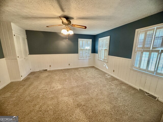 839 Golf Dr, Swainsboro, GA 30401 - unfurnished room featuring ceiling fan, a textured ceiling, visible vents, a wainscoted wall, and carpet flooring