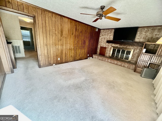 839 Golf Dr, Swainsboro, GA 30401 - unfurnished living room with a ceiling fan, a textured ceiling, a brick fireplace, wooden walls, and carpet