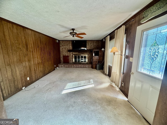 839 Golf Dr, Swainsboro, GA 30401 - unfurnished living room featuring a fireplace, carpet floors, a textured ceiling, wood walls, and a ceiling fan