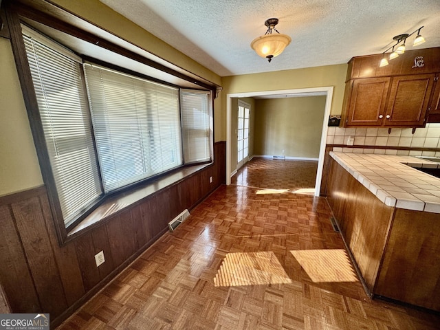 839 Golf Dr, Swainsboro, GA 30401 - kitchen with backsplash, a textured ceiling, visible vents, wood walls, and tile counters