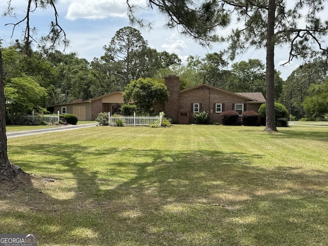 839 Golf Dr, Swainsboro, GA 30401 - view of property exterior featuring fence, a yard, a chimney, brick siding, and driveway