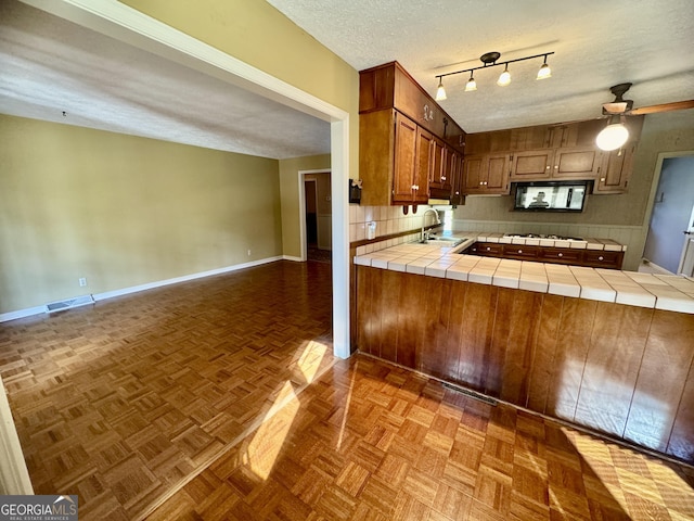 839 Golf Dr, Swainsboro, GA 30401 - kitchen featuring ceiling fan, a textured ceiling, a sink, a peninsula, and tile counters