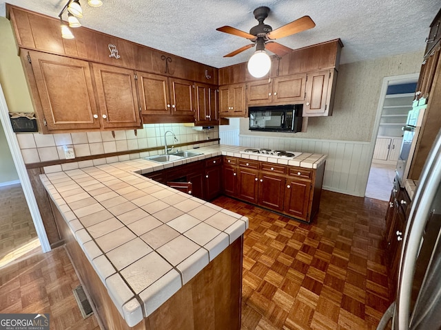 839 Golf Dr, Swainsboro, GA 30401 - kitchen with a peninsula, black microwave, white stovetop, tile counters, and a sink