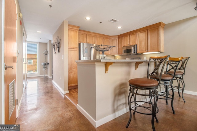 1133 Church Unit 1, Covington, GA 30014 - kitchen featuring stainless steel appliances, finished concrete flooring, baseboards, a kitchen breakfast bar, and a peninsula