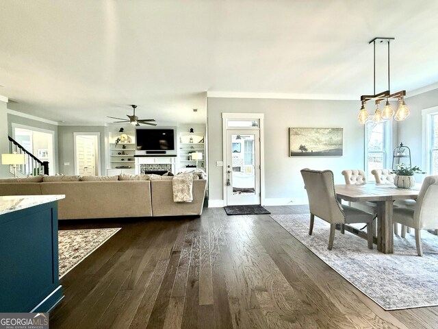 305 Red Gate Ln, Canton, GA 30115 - dining space with ceiling fan, a fireplace, dark wood finished floors, ornamental molding, and stairs