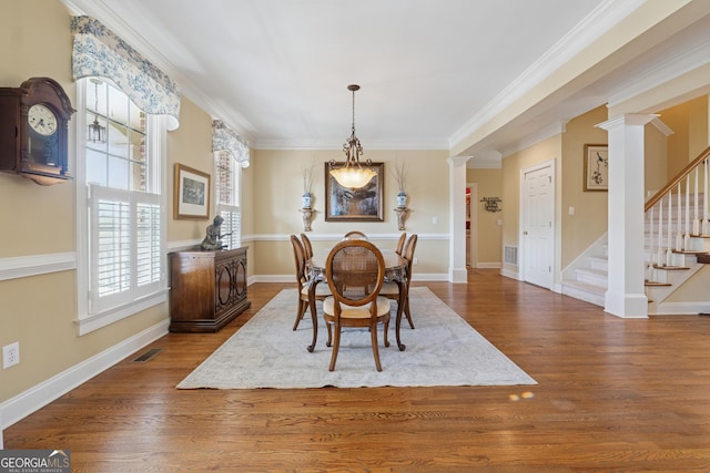 dining area featuring visible vents, wood finished floors, and ornate columns