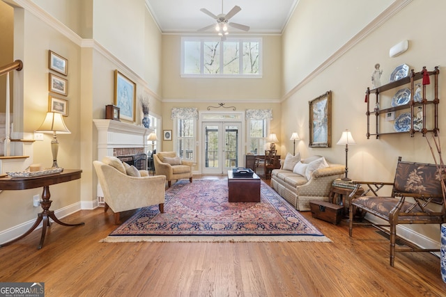 living room with a wealth of natural light, wood finished floors, ceiling fan, and crown molding