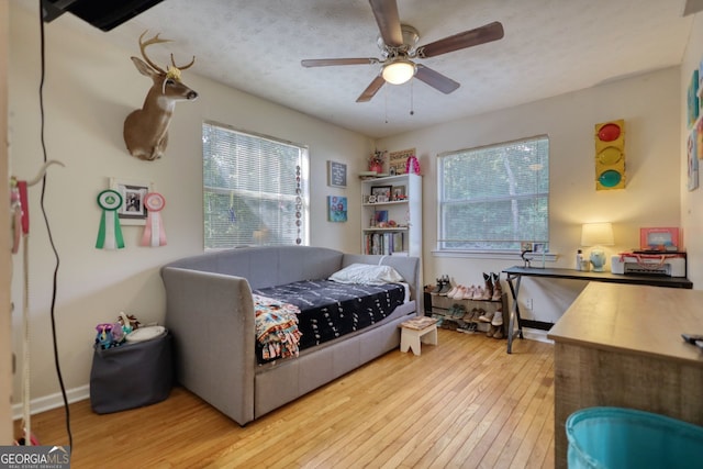 bedroom with hardwood / wood-style floors, a ceiling fan, multiple windows, and a textured ceiling