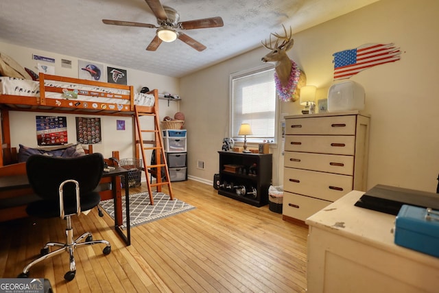 bedroom featuring light wood finished floors, baseboards, and a textured ceiling