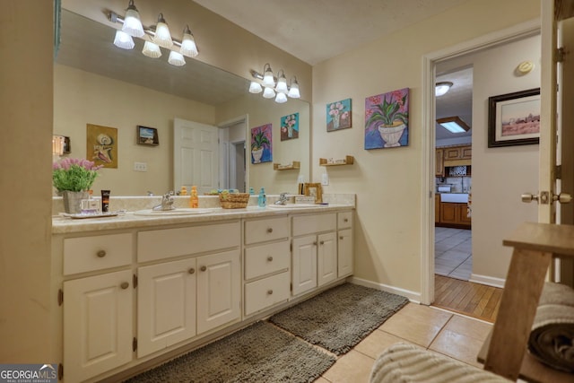 bathroom with tile patterned floors, a sink, double vanity, and baseboards