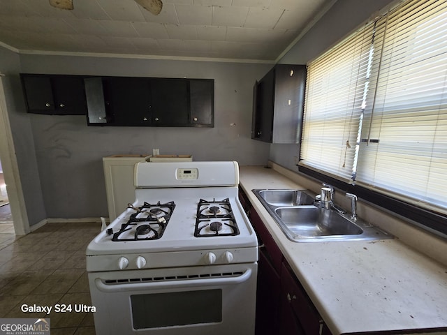 kitchen featuring white range with gas cooktop, ornamental molding, a sink, and dark cabinets