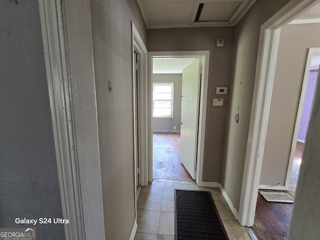 hallway with baseboards, ornamental molding, and visible vents