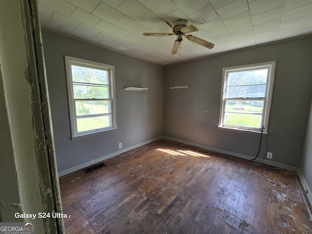 spare room featuring a wealth of natural light, visible vents, hardwood / wood-style flooring, and a ceiling fan