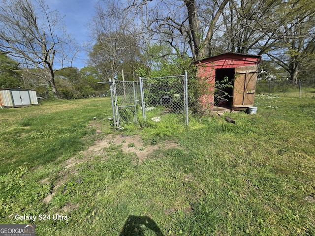 view of yard with a storage unit, a gate, an outbuilding, and fence