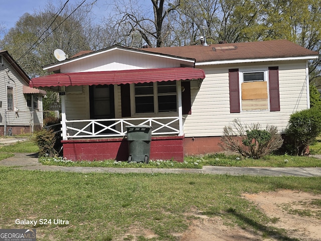 view of front facade featuring crawl space, a front yard, a shingled roof, and covered porch