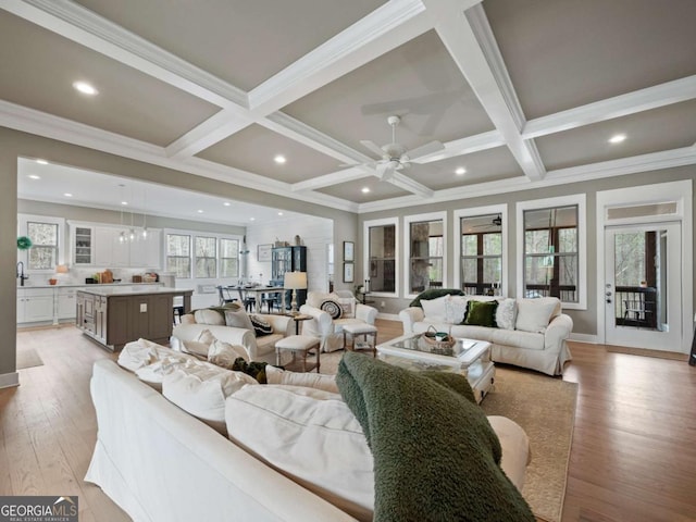 living room with light wood-style flooring, ornamental molding, coffered ceiling, and beamed ceiling