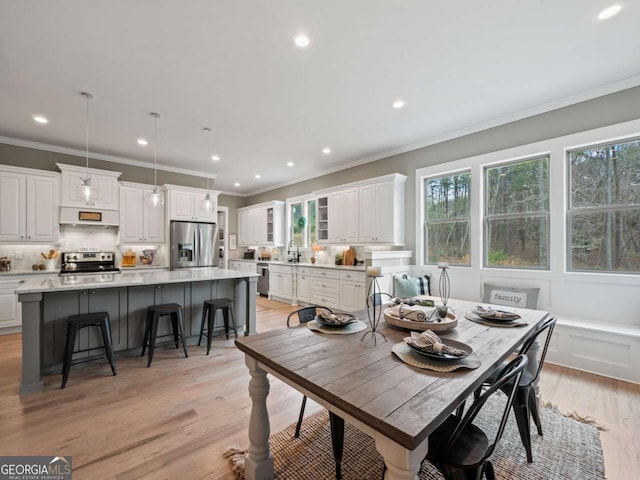 dining room with recessed lighting, crown molding, and light wood-type flooring