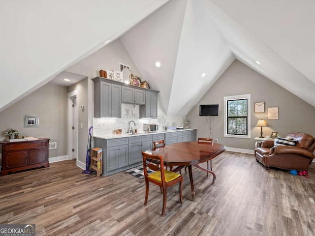 dining space with baseboards, wood finished floors, and vaulted ceiling