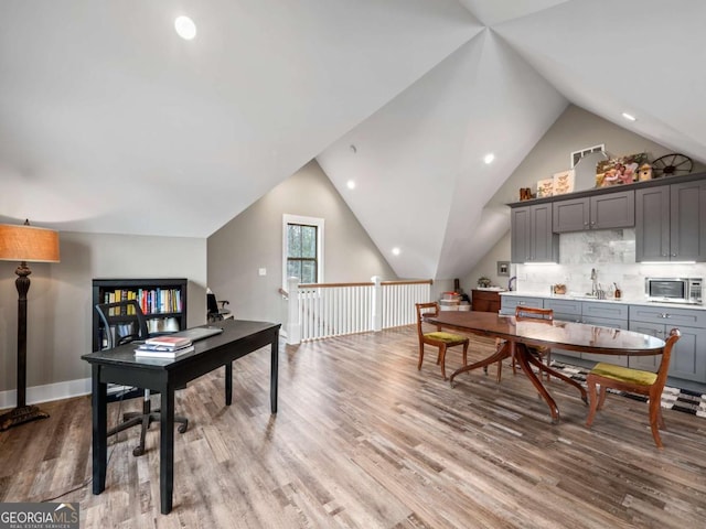 home office featuring light wood-type flooring, recessed lighting, a sink, and vaulted ceiling