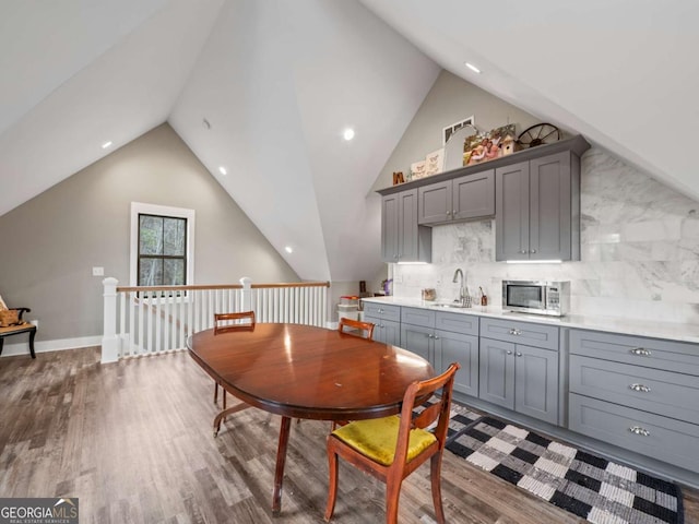 dining space featuring vaulted ceiling, recessed lighting, baseboards, indoor wet bar, and wood finished floors