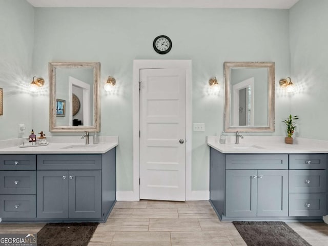 full bath featuring a sink, two vanities, and baseboards