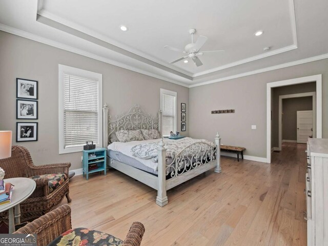 bedroom with crown molding, a raised ceiling, baseboards, light wood-style floors, and recessed lighting