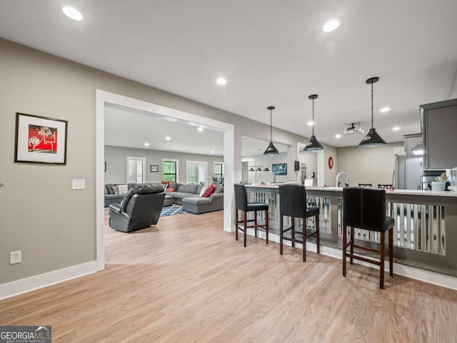 kitchen featuring hanging light fixtures, baseboards, light wood-style floors, and recessed lighting