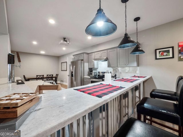 kitchen featuring recessed lighting, under cabinet range hood, gray cabinetry, a peninsula, and appliances with stainless steel finishes