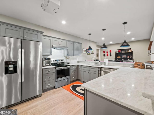 kitchen featuring light wood-style flooring, appliances with stainless steel finishes, under cabinet range hood, a sink, and gray cabinets