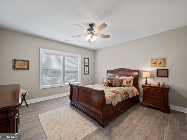 bedroom featuring baseboards, visible vents, wood finished floors, and a ceiling fan