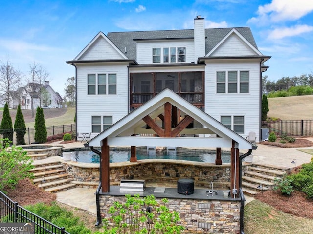 back of property with a chimney, a sunroom, stairway, and a patio