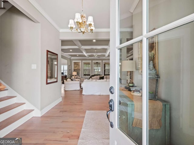 foyer entrance with coffered ceiling, ornamental molding, a chandelier, beamed ceiling, and wood finished floors