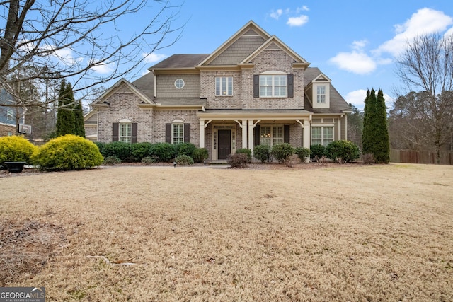 view of front facade with brick siding, a front lawn, and covered porch