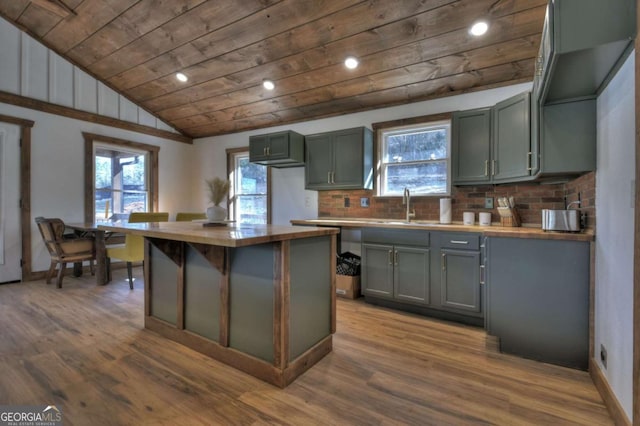 kitchen featuring tasteful backsplash, vaulted ceiling, wood ceiling, wood finished floors, and a sink