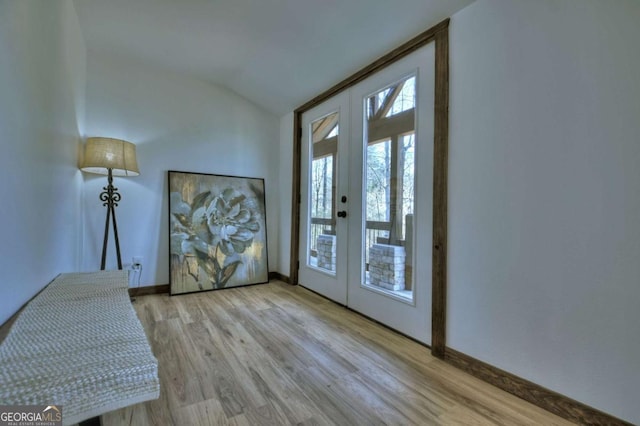 doorway featuring french doors, wood finished floors, baseboards, and lofted ceiling