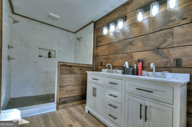 full bathroom with a walk in shower, double vanity, a sink, and wood finished floors