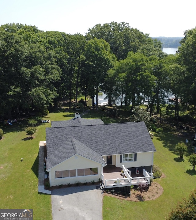 country-style home featuring a chimney, covered porch, and a front yard