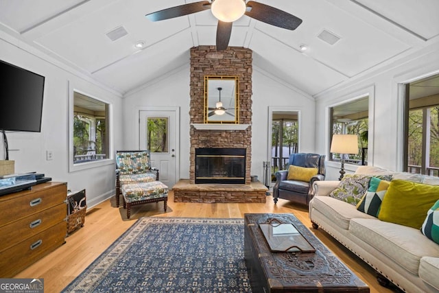 living area featuring plenty of natural light, a ceiling fan, a stone fireplace, and wood finished floors