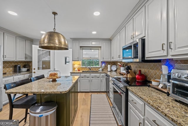 kitchen with appliances with stainless steel finishes, decorative backsplash, a center island, ornamental molding, and light stone countertops